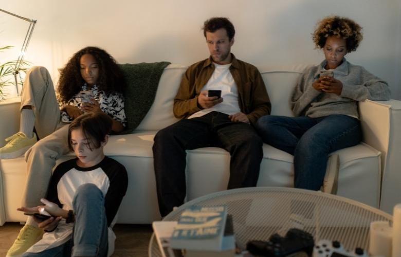 Family sitting on sofa holding cellphones