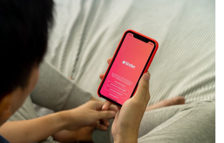 A man starting the tinder app on his iPhone