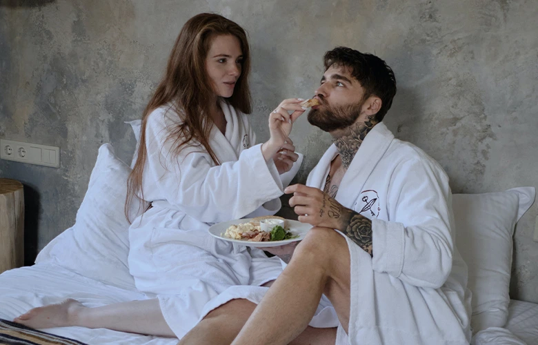 A gemini and cancer couple eating on bed